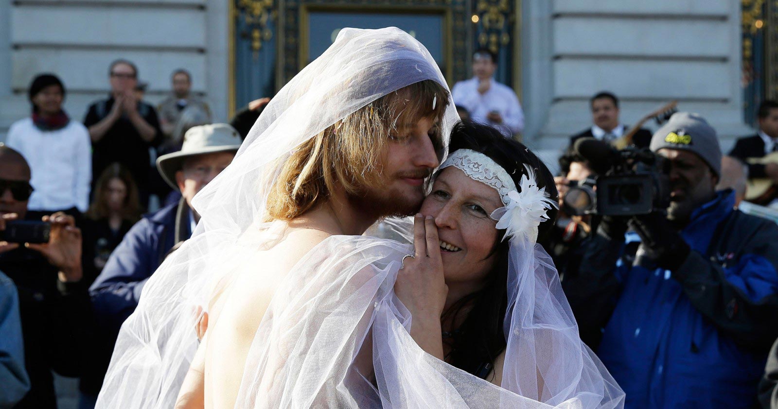 Gypsy Taub, right, embraces Jaymz Smith, left, following their nude wedding outside City Hall Thursday, Dec. 19, 2013, in San Francisco. Taub, the face and body of San Francisco's nude rights movement, tied the knot outside City Hall and was later cited and released by police. Taub, a mother of three who conducts nude interviews on public access TV, has been arrested repeatedly for violating the city's public nudity ban. (AP Photo/Eric Risberg)