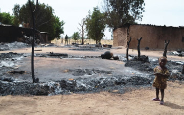 A little girl and a security operative at one of the scenes of the Kawuri, Borno State Boko Haram attack ... on Tuesday. | Photo: AFP.