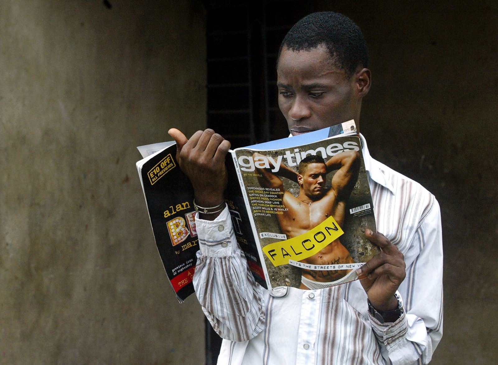 Gay activist Bisi Alimi, 27, looks at a copy of Gay Times magazine in front of his house in Lagos, Nigeria, Wednesday, Oct. 11, 2006. A proposed law in Nigeria would outlaw not just gay marriages, but any form of association between gay people, social or otherwise, and publication of any materials deemed to promote a "same-sex amorous relationship." Alimi has been trying to drum up opposition to the legislation, but says Nigeria's homosexual community is so far underground and the subject is so taboo that it's been difficult. (AP Photo/Sunday Alamba)