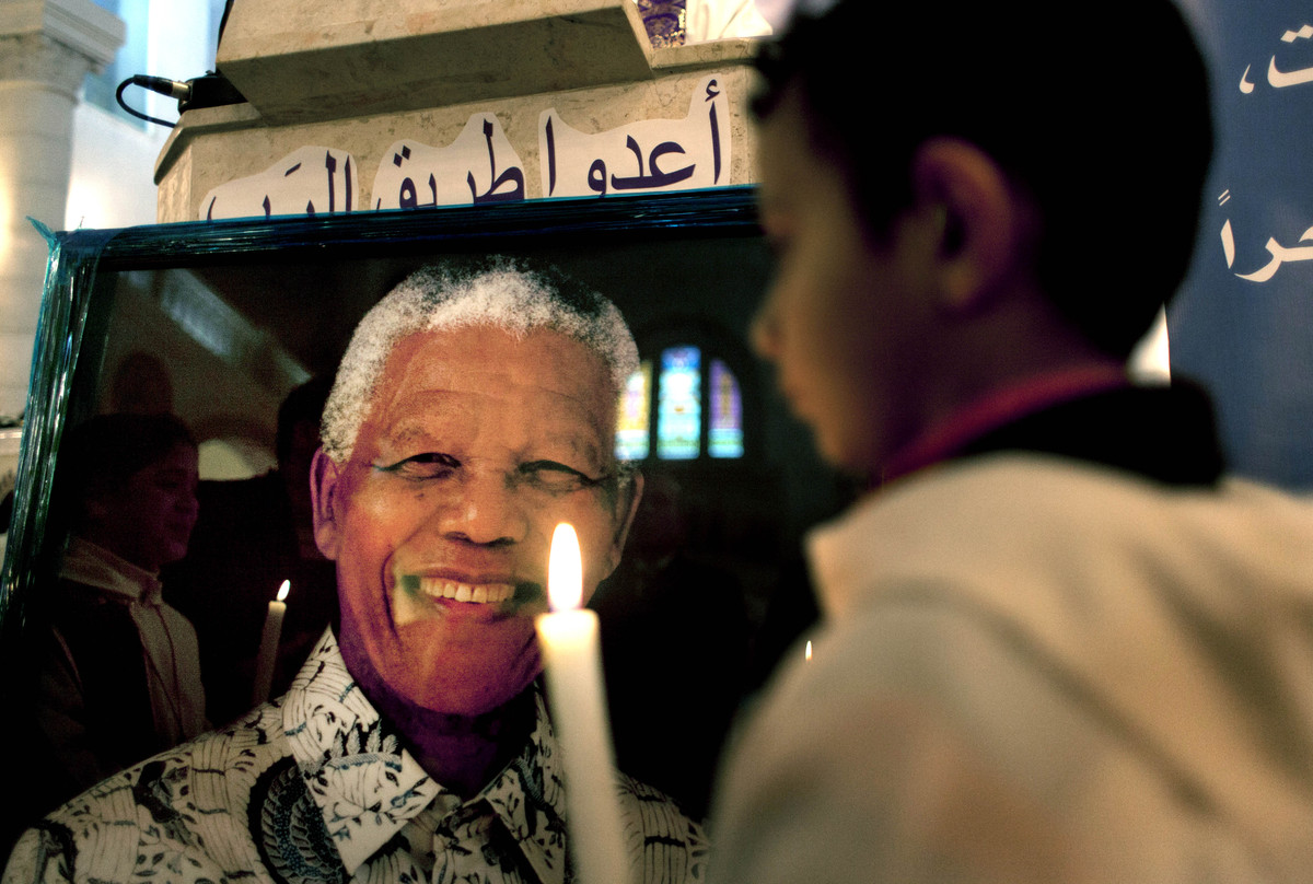 A choir sings hymns during a special service in the honor of late South African leader Nelson Mandela at the Holy Family Church, in the West Bank city of Ramallah, Sunday Dec. 8, 2013. Palestinians mourned Nelson Mandela as a loyal champion of their cause, lighting candles for him in special church services on Sunday and holding up his picture in confrontations with Israeli troops in the West Bank. (AP Photo/Nasser Nasser)