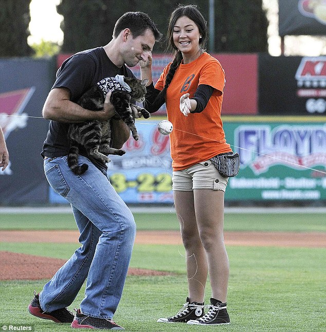Feline fine: Hero cat Tara, with the help of her owner Roger Triantafilo and team staff member Jade Henry (right), 'tosses' the first pitch at the start of the Bakersfield Blaze and Lancaster Jayhawks game