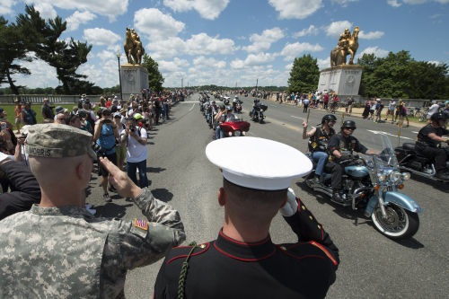 Army Pfc. Colin Morris, left, and Marine Cpl. Zach Powers, center, salute participates of Rolling Thunder 'Ride for Freedom' event in Washington, Sunday, May 25, 2014. (Molly Riley/AP)