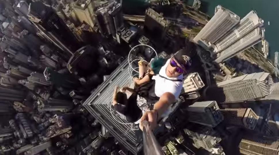 Daniel Lau takes selfie atop a towering skyscraper in Hong Kong. [Photo Credit: Frank Wu/You Tube] 
