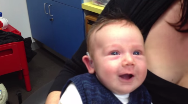 Lachlan’s face breaks into a cheeky smile upon hearing his parents for the first time (photo credit]: Toby Lever/YouTube)