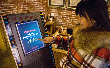 A customer uses a face-scanning machine at the restaurant. (Photo Credit:Corbis)