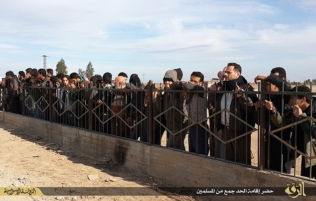A crowd watched on as ISIS terrorists beheaded a man for alleged witchcraft in a rural area named Aldbsa, to the west the city of Raqqa. (Photo Credit: Mail Online)