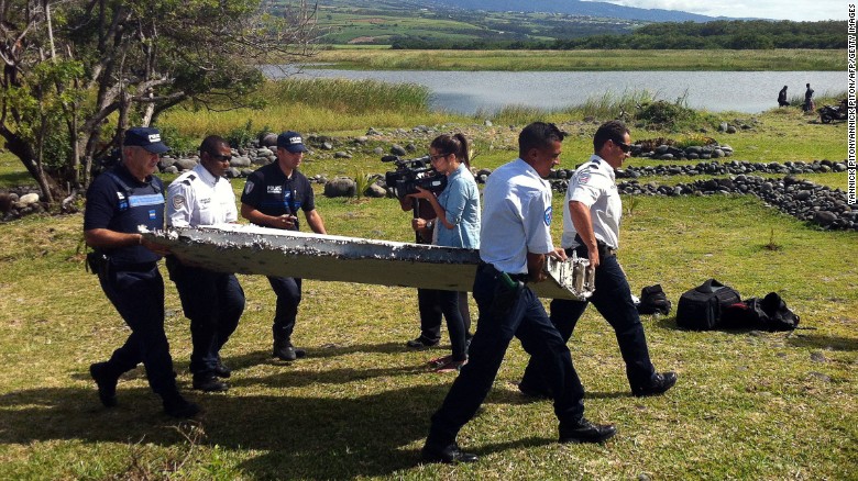 Police carry a piece of debris from an unidentified aircraft found off the coast of Reunion island. oto Credit: Yannick Piton)