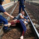 Hungarian-policemen-stand-by-the-family-of-migrants-protesting-on-the-tracks-at-the-railway-station-in-the-town-of
