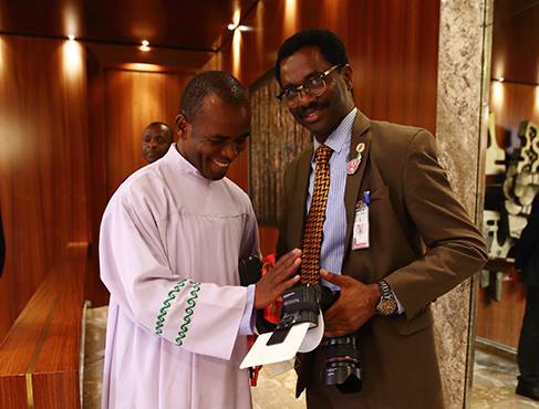 Reverend Father Ejike Mbaka blessing the camera of Sunday Aghaeze‎, Personal Assistant On Photography to President Muhammadu Buhari on Sunday, February 28, 2016 in Aso Rock, Abuja.