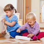 Two children playing with electricity on floor at home