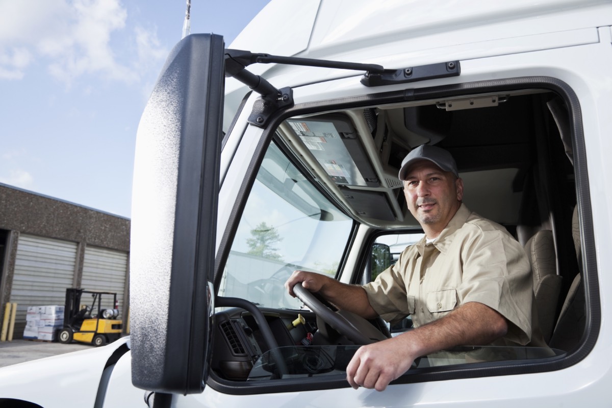 Truck driver (30s) sitting in cab of semi-truck. professions stamina