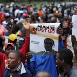 Demonstrators hold anti-Mugabe placards