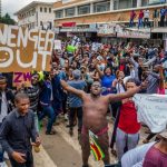 People carry placards and react during a