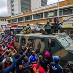 People cheer a passing Zimbabwe Defense