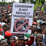 People hold an anti-Grace Mugabe placard