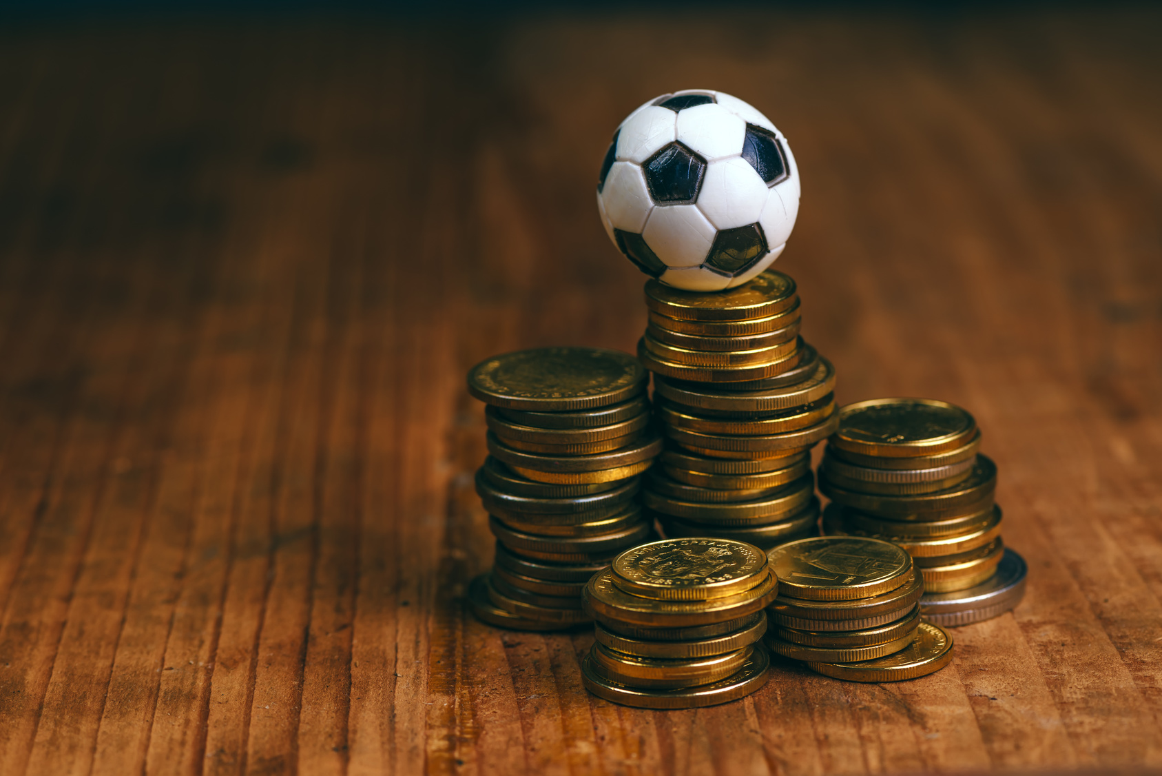 Soccer bet concept with small football on top of coin stack, making money by predicting sport results. betting