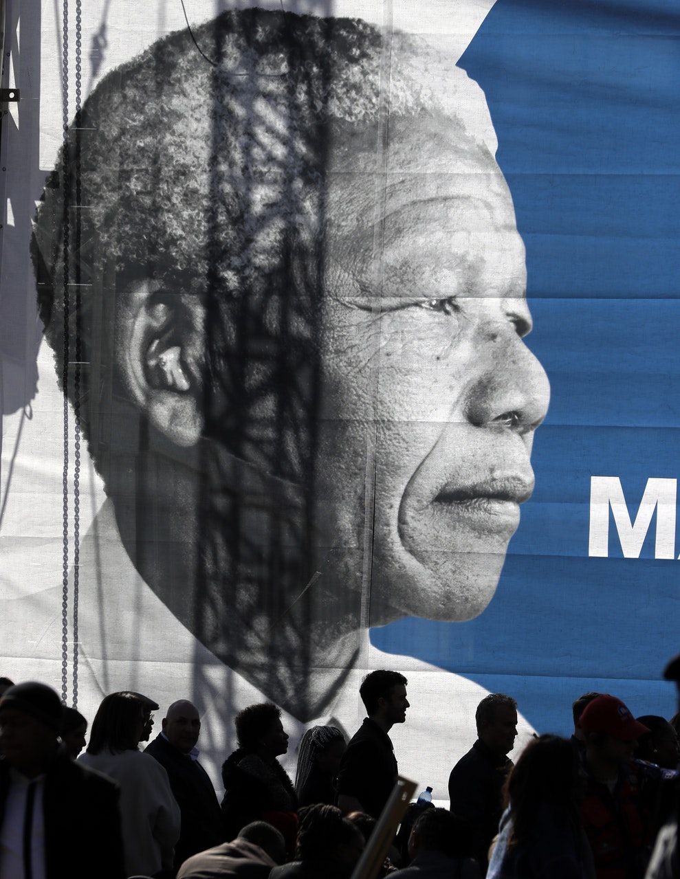 People gather below a giant banner of the late Nelson Mandela (Themba Hadebe/AP)