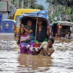 floods flooding  People use cycle rickshaws to commute through a flooded road after heavy rains in Guwahati