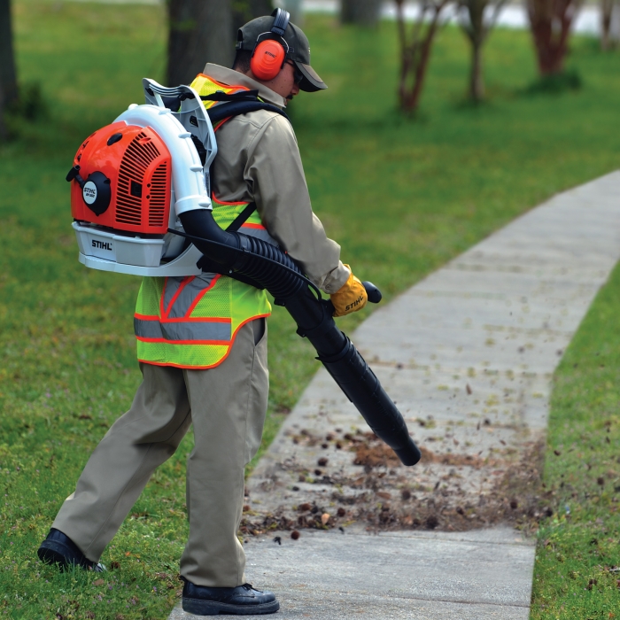 A man wearing the proper safety gear while using a leaf blower.