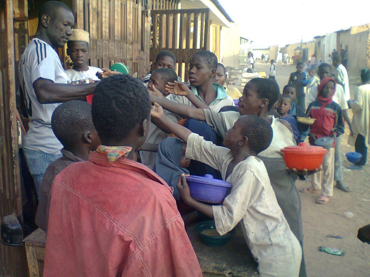 A group of Almajiri children struggling for alms given them by a trader in Northern Nigeria