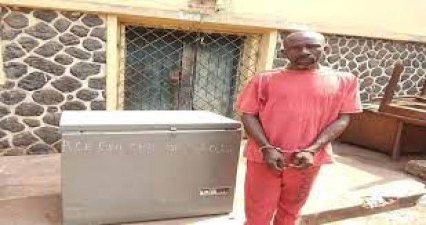 FATHER FROM HELL: The suspect, Ifeanyi Amadikwa pictured with the freezer the children were found in at the police station in Enugu State where he was arrested in January 2022