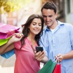 Young couple with shopping bag using mobile phone