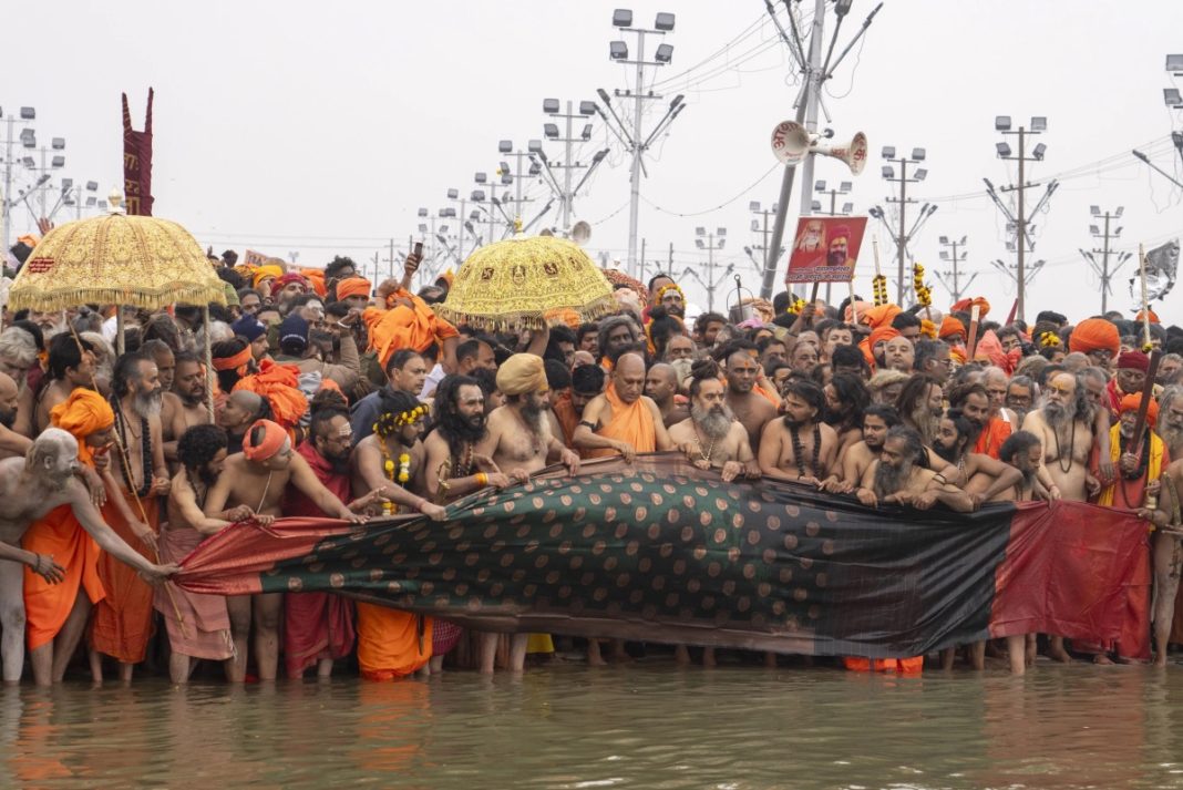 Naked Hindu ascetics and holy men and their guru offer a cloth to the water as the prepare to bathe at the confluence of the Ganges, the Yamuna and the mythical Saraswati rivers on the second day of the 45-day-long Maha Kumbh festival in Prayagraj, India, Tuesday, Jan. 14, 2025. | AP Photo/Ashwini Bhatia