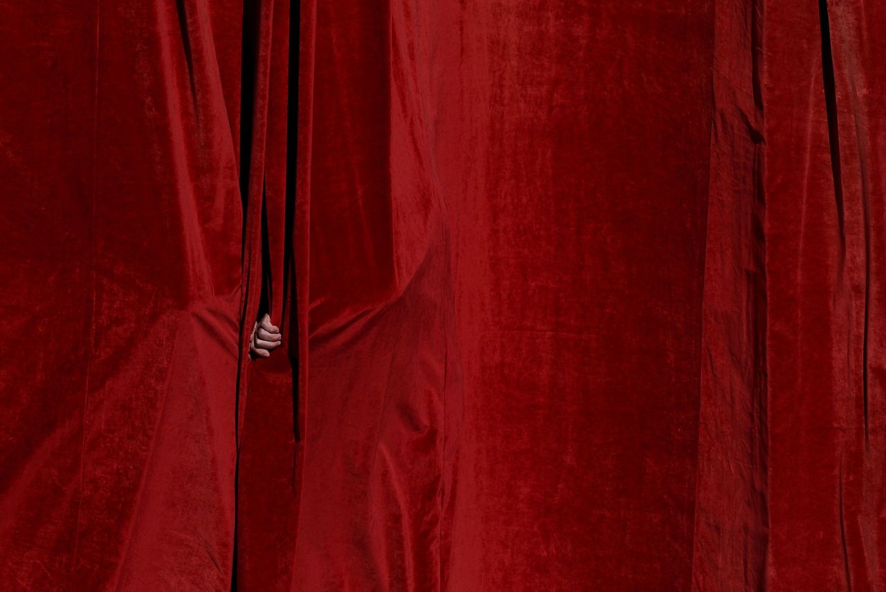 A person peeks through a curtain during the funeral. Kai Pfaffenbach/Reuters