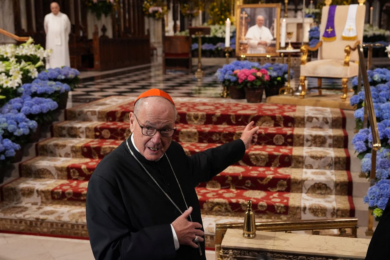 Archbishop of New York Cardinal Timothy Dolan points to an image of Pope Francis as he addresses the media at St. Patrick's Cathedral in Manhattan on Monday, April 21, 2025. | Adam Gray/Reuters  