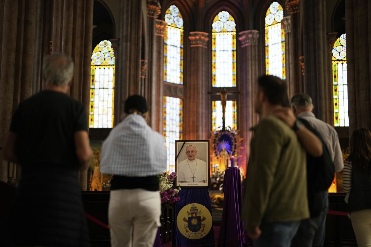 People stand next to a photograph of Pope Francis placed at Saint Anthony Catholic church in Istanbul, Turkey on Monday, April 21, 2025. | Khalil Hamra/AP