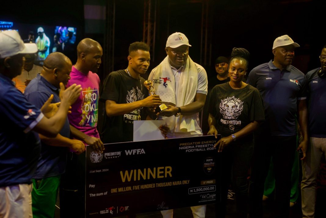 Valentine Ozigbo, Chairman of Feet ’ N’ Tricks International, presents the champion’s trophy to Ezeakabudu “BlessedChild,” winner of the men’s category, at the Predator Energy Nigerian Freestyle Football Championship 2024, held in Lagos on Saturday, September 21, 2024. Standing beside them is Oraka Nvy, Managing Director of Feet ’ N’ Tricks International.
