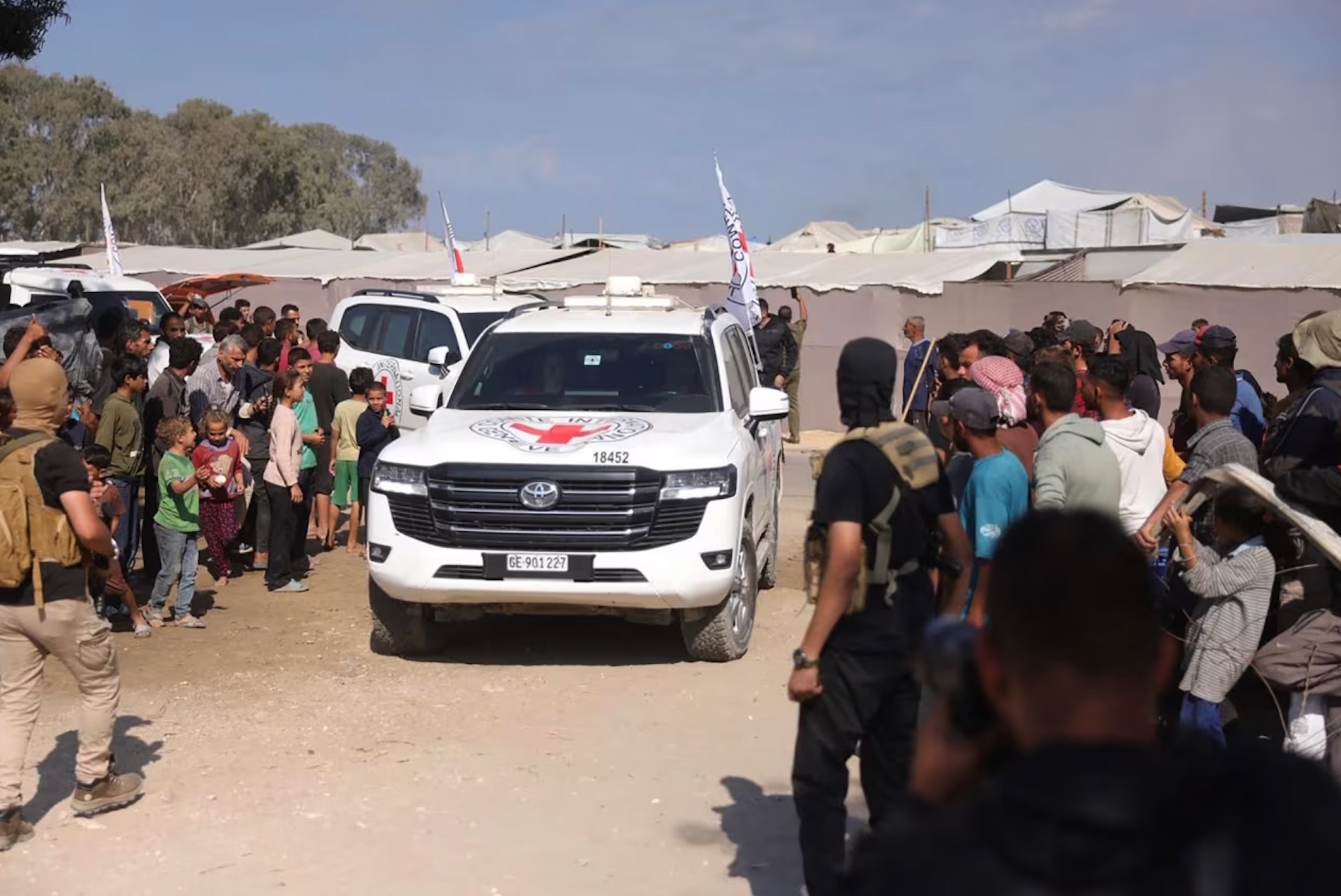 Palestinians gather on the sides of the road as International Red Cross vehicles arrive to transport the second batch of released Israeli hostages on Monday, October 13, 2025. | Bashar Taleb/AFP/Getty Images