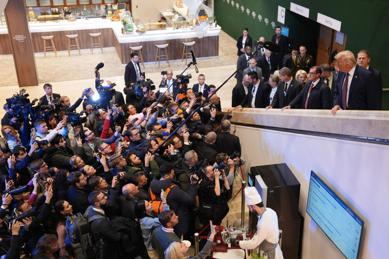 Former U.S. President Donald Trump speaks with journalists and supporters as reporters crowd around him during a visit to a food court area at the World Economic Forum in Davos, Switzerland in January 2026. | Getty Images