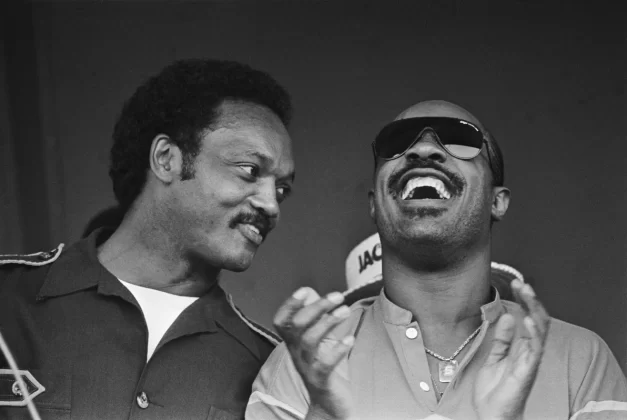 Jackson leans towards singer Stevie Wonder as he leads a crowd in a rendition of the campaign chant