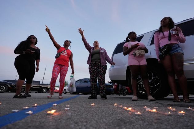 People gesture after lighting candles during a prayer vig
