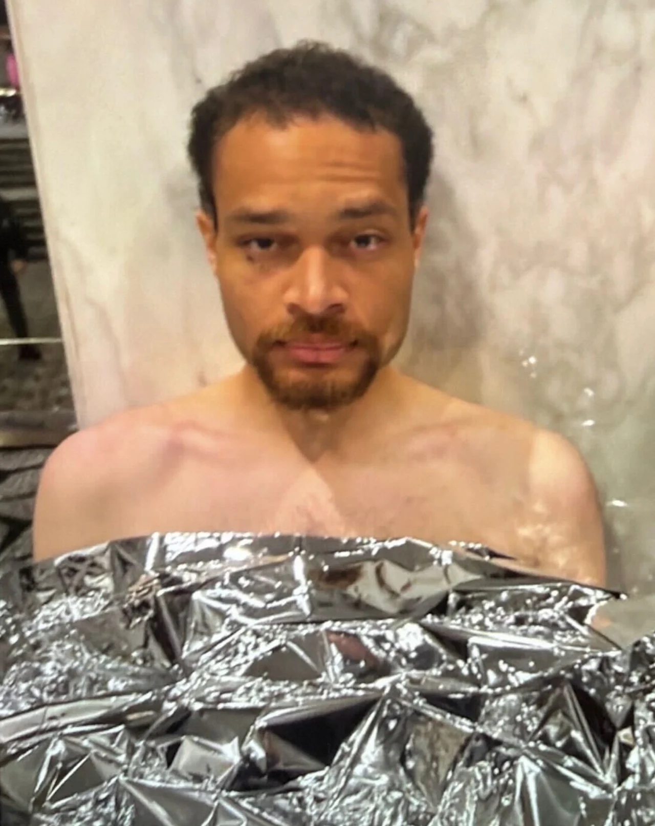 In a photo obtained by CNN, Cole Tomas Allen is seen covered with a mylar blanket after being arrested and his clothes removed by officers who searched him for weapons and wounds. Obtained by CNN