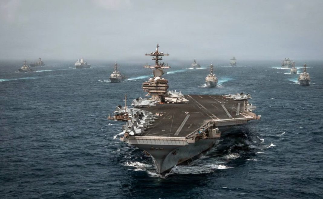 A U.S. Navy aircraft carrier sails with escort vessels during maritime operations in waters near the Strait of Hormuz in an undated handout photograph.