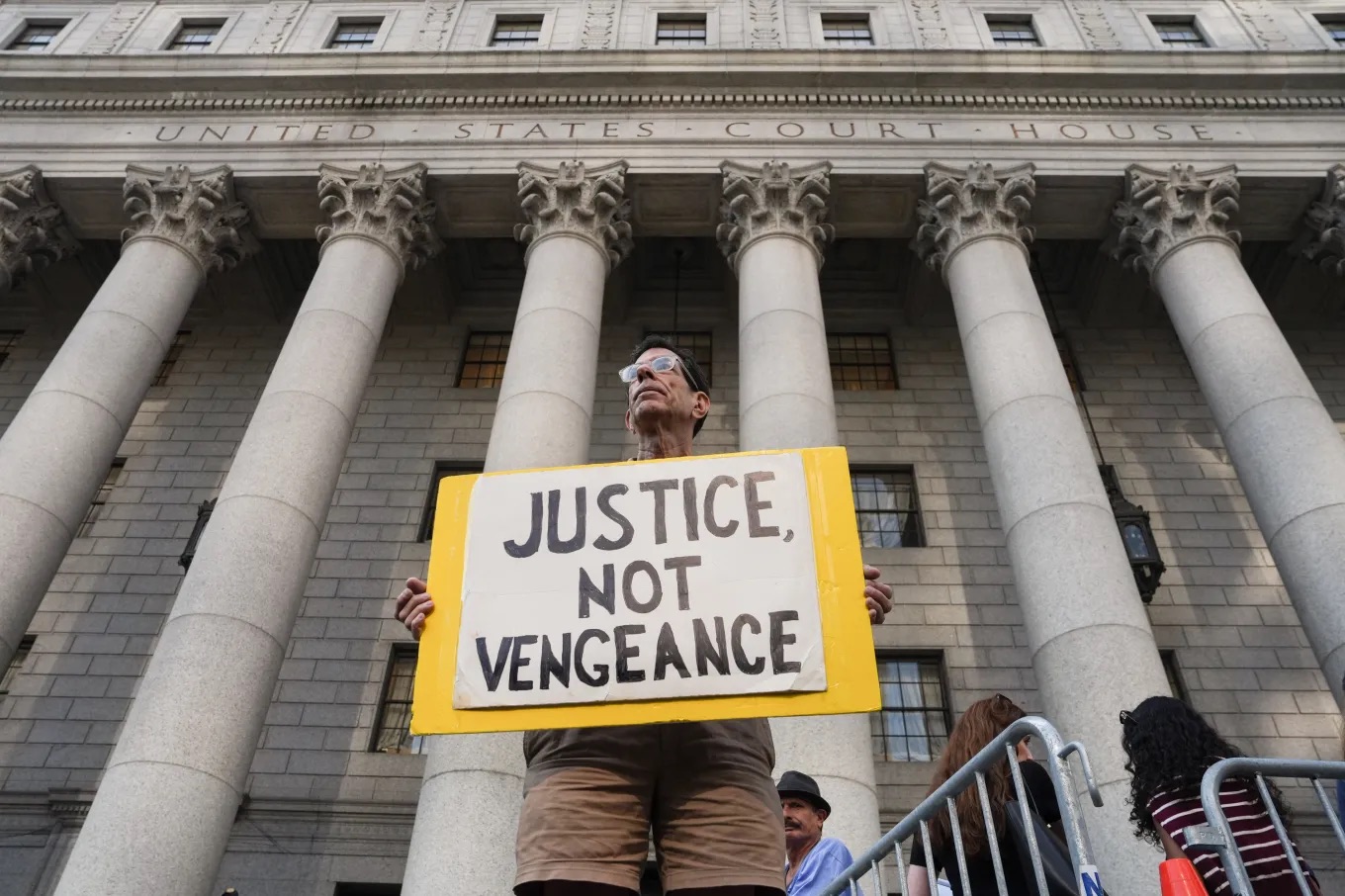 A man holds a sign outside of Manhattan Federal Court on the day of a hearing for Luigi Mangione on August 14, 2026, in New York.