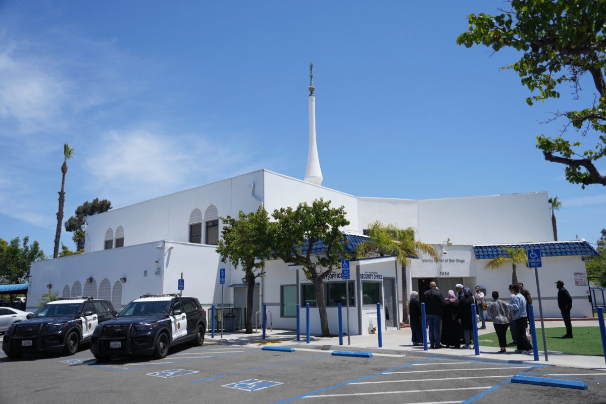 People gather outside the Islamic Center of San Diego as police vehicles remain at the scene a day after a deadly shooting on May 19, 2026.