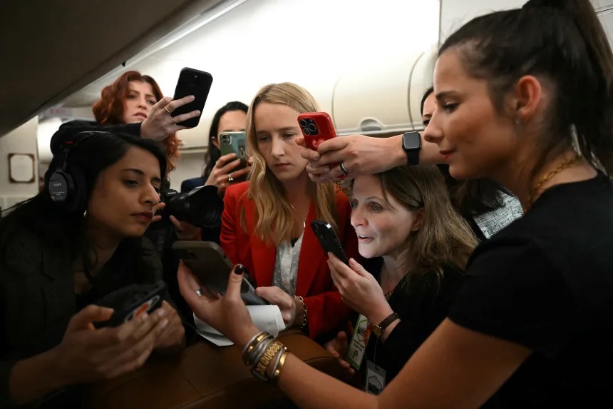 CNN's Kit Maher, center, and other members of the press look at a statement from White House Press Secretary Karoline Leavitt about a reported suspicious package on President Donald Trump's route to Palm Beach International Airport, aboard Air Force One