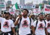 Former Minister Blasts Borno Governor Over Arrests of ‘Tinubu Must Go’ T-Shirt Wearers An illustration generated with artificial intelligence shows Nigerian youths wearing “Tinubu Must Go” shirts and carrying placards during a street protest. | The Trent