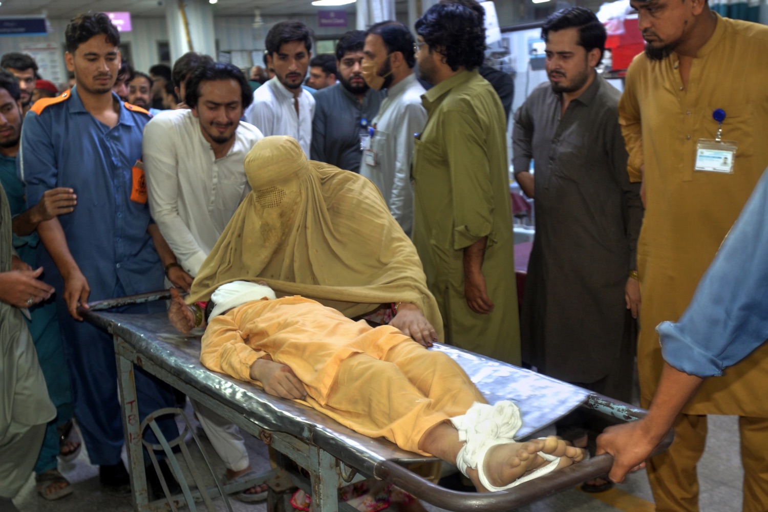 A woman mourns next to the body of a boy, who was killed in the roof collapse of a private school, at a hospital in Peshawar,