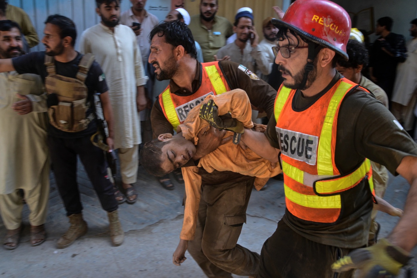 Rescue workers carry an injured boy after rescuing him from the rubble of a roof collapse at a private school,